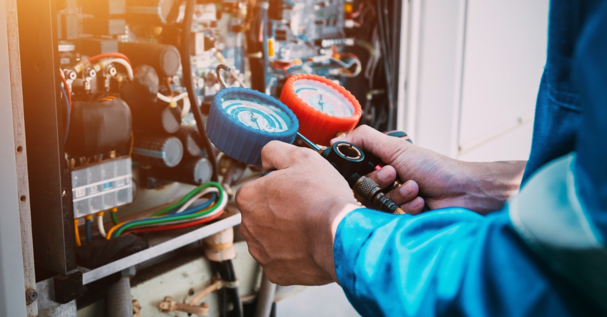 Technician checking an outdoor air conditioner unit for a refrigerant leak during a home service visit.